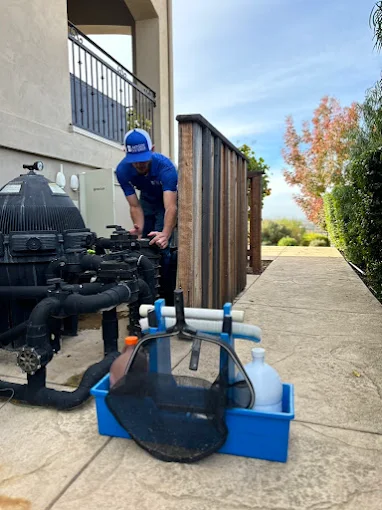 Technician inspecting pool pump and plumbing equipment